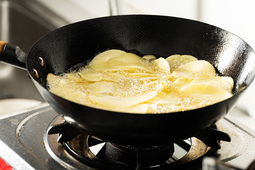Frying potato slices in a pot.