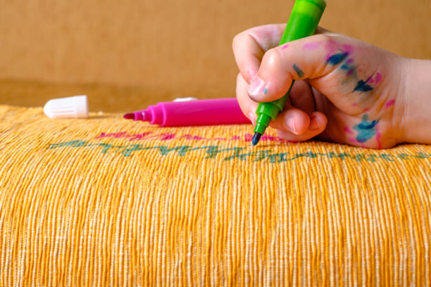 Dirty children hand in colored markers drawing with a green felt-tip pen of the couch