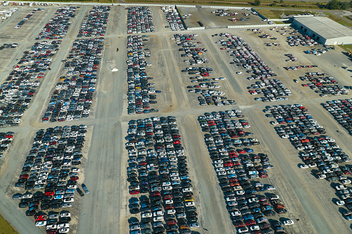 View from above of big parking lot with parked used cars after accident ready for sale. Auction reseller company selling secondhand broken vehicles for repair.