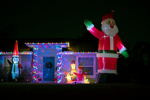 Brightly illuminated Christmas decorations on front yard of Florida family home. Outside decor for winter holidays.