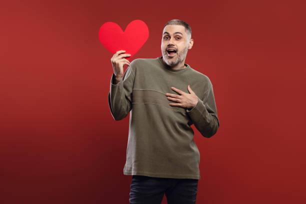istock man holding a paper heart at face height 1785840357
