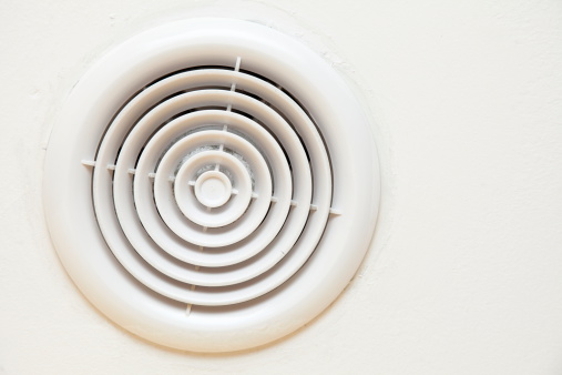 circular plastic air vent in white wall ventilation grille