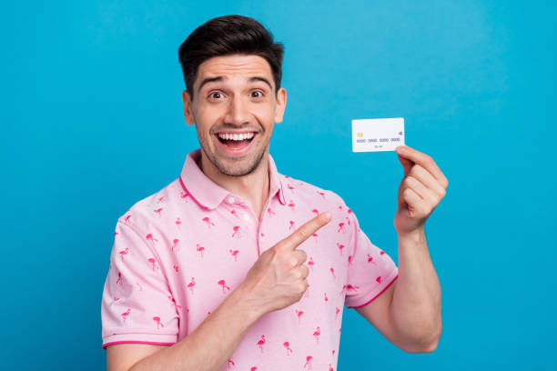 istock Photo of impressed handsome guy indicate finger hand hold plastic debit card isolated on blue color background 1785845526