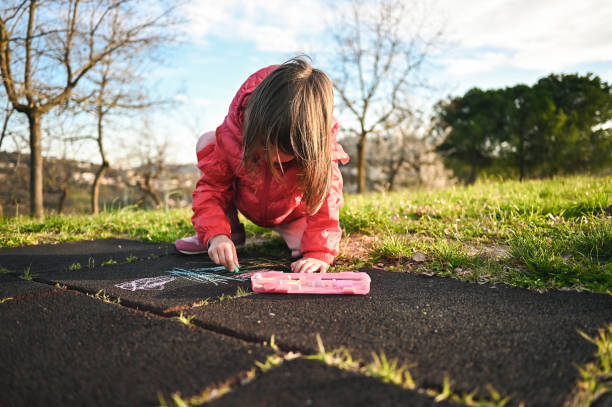 istock Cute little girl chalking on a ground in springtime. 1785849743