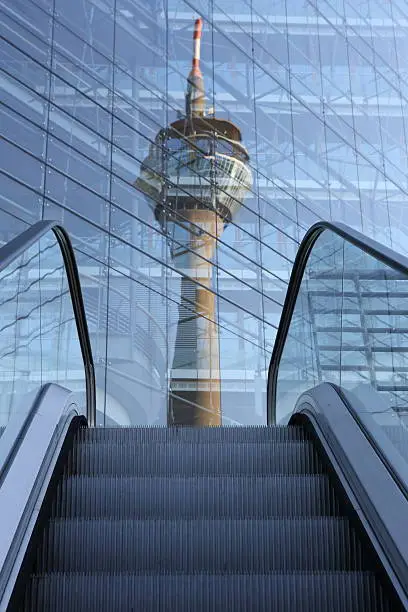 Düsseldorf Rheinturm reflected in office building with an escalator close-up in the front