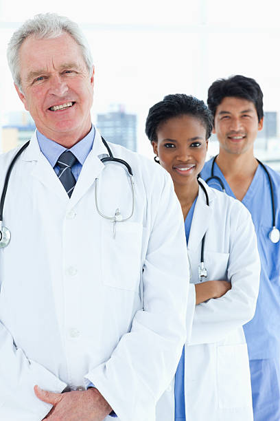 istock Mature doctor standing upright with two smiling medical interns 178587421