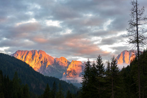 Last rays of the sunset on rocky peaks with pink clouds above Dolomites, Sappada, Friuli-Venezia Giulia, Italy