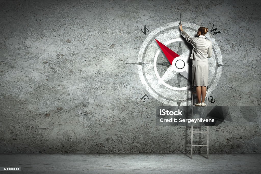 Businesswoman on a ladder drawing compass on wall Businesswoman drawing compass with finger on wall Activity Stock Photo