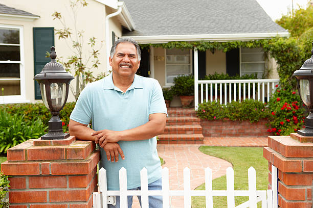 Senior man standing outside his home leaning on gate post
