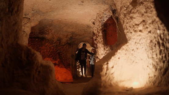 Two female tourist friends are visiting an underground city in Cappadocia Türkiye Turkey during their travel.