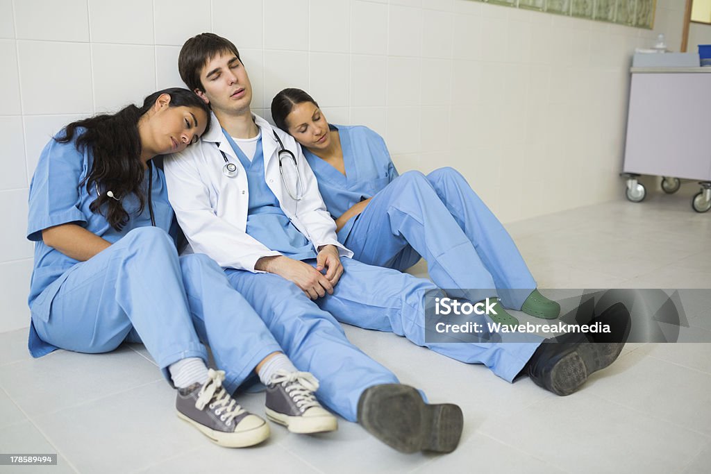 Nurses and doctor sleeping while sitting on the floor Nurses and doctor sleeping while sitting on the floor of a hospital hallway Nurse Stock Photo