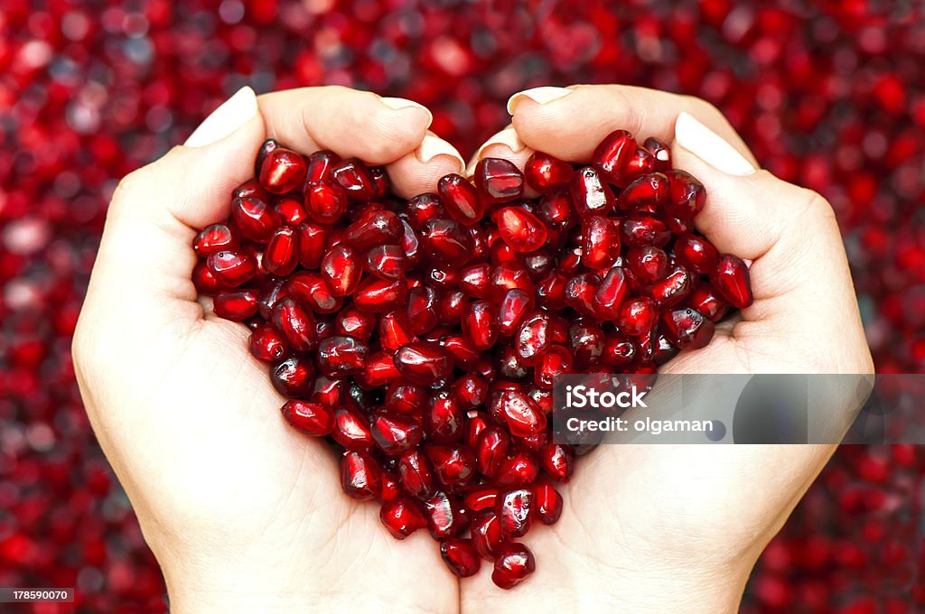 Pomegranate seeds shaping heart in hands Pomegranate seeds in woman hands shaping heart symbol Pomegranate Stock Photo