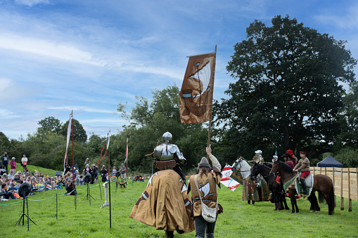 Medieval warrior with chain mail headwear and a sword standing outdoors