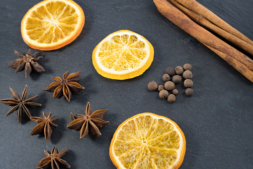 Gingerbread spices: star anise, allspice, cinnamon and orange slices on slate board