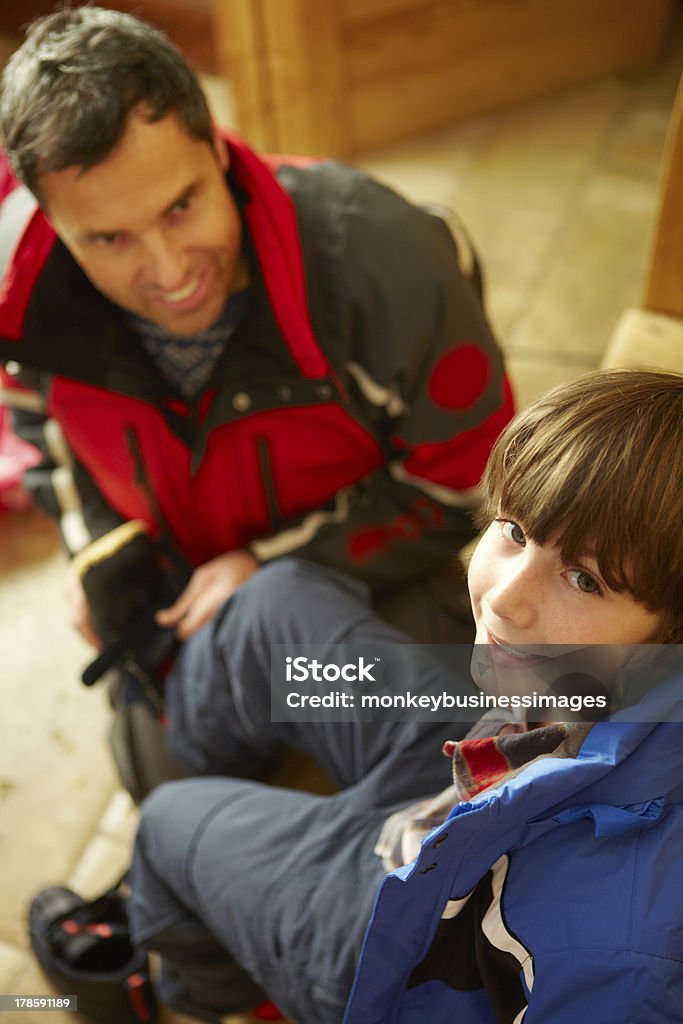 Padre aiutando il figlio a indossare vestiti caldi all'aperto - Foto stock royalty-free di Abbigliamento da sci