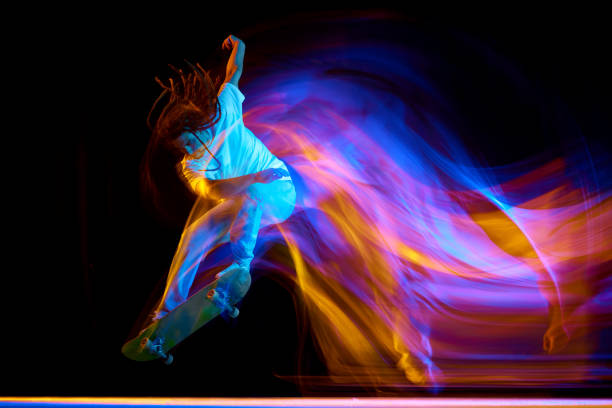 istock Man skateboarder performing freestyle tricks in motion isolated black background in mixed neon flashes of light. Concept of youth culture. 1785916942