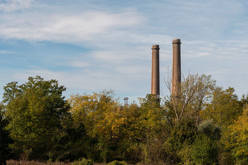 Two chimneys of a thermal power station behind trees