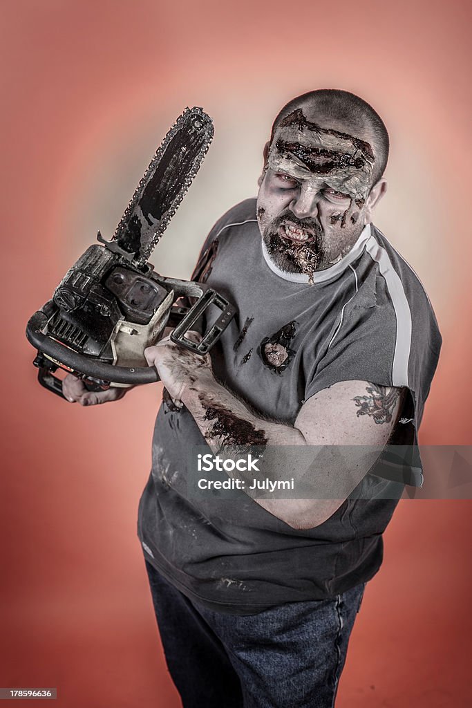 zombie with mechanical saw is a man disguised as a zombie one with mechanical saw Bizarre Stock Photo