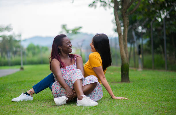 istock young women sitting in a meadow in the open air looking at each other while smiling 1785967647