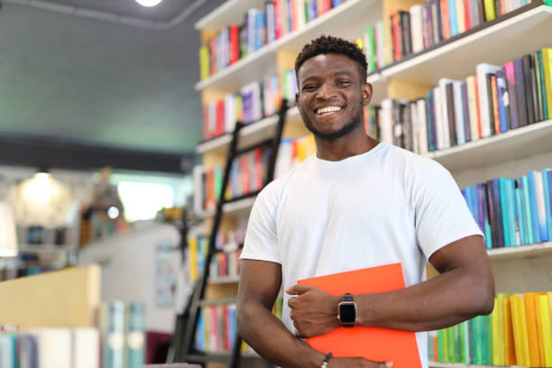 Cheerful young man in a university library, immersed in academic pursuits, reflecting positive and intelligent learning.