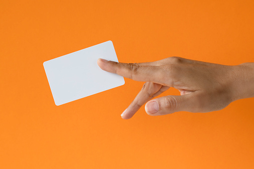 Close-up of a card in a woman's hand isolated on orange background.
