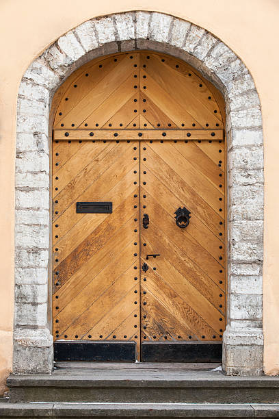 istock Old uncolored wooden door in building facade with arch 178600409