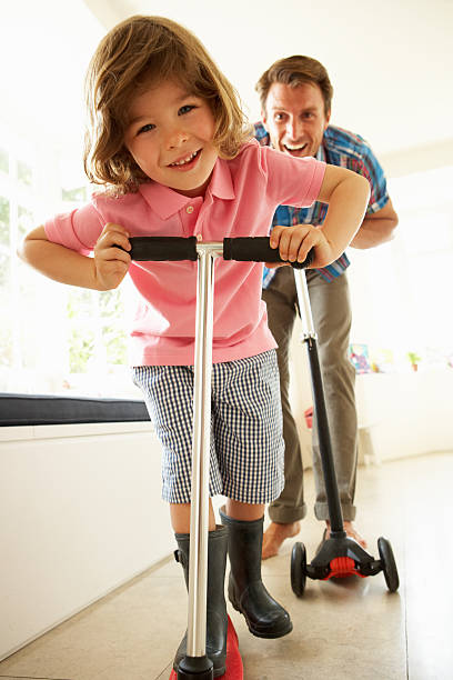 istock Father And Son Riding Scooters Indoors 178600596
