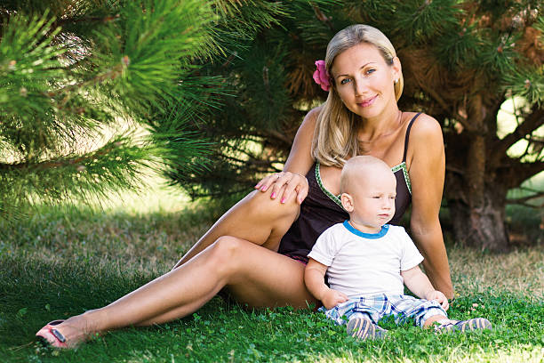 Bella donna con un bambino seduto sull'erba - foto stock