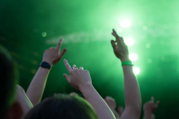 tłum ludzi uczestniczących w występie muzycznym z rękami uniesionymi do góry. jasnozielone światło wydobywające się z reflektorów scenicznych - arms raised green jumping hand raised zdjęcia i obrazy z banku zdjęć