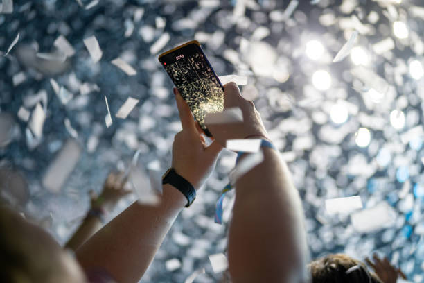 istock Crowd of people attending a musical performance and taking photos. White confetti falling down on audience 1786024141