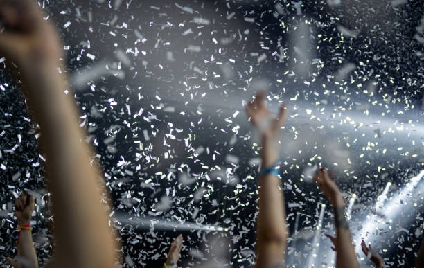 istock Crowd of people attending a musical performance. Putting hands up. White confetti falling down on excited audience 1786024144