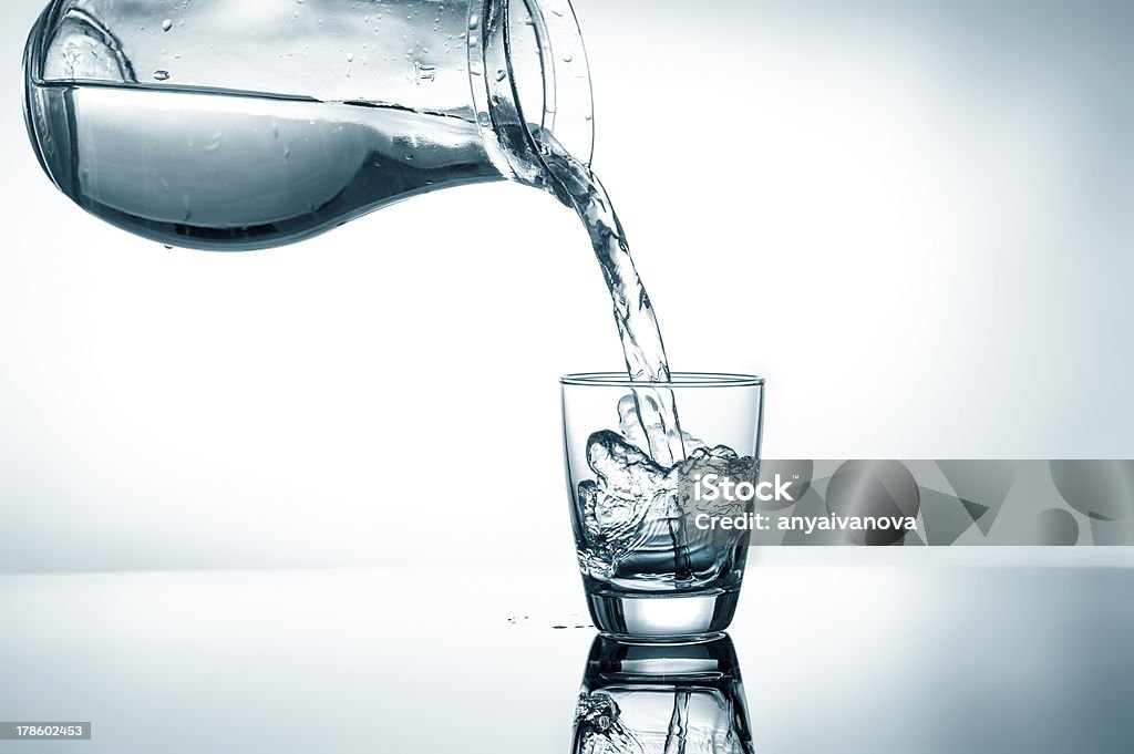 Filling in glass of water Pouring water from pitcher into a glass Water Stock Photo