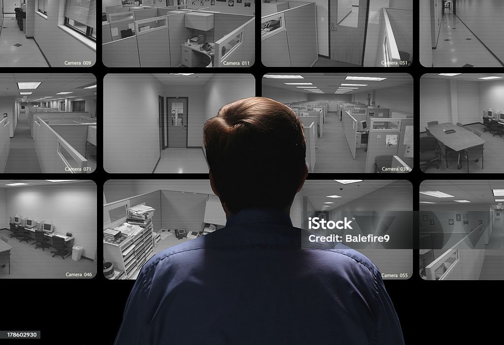 Security guard conducting surveillance by watching several monitors Security guard conducting surveillance by watching several security monitors Security Camera Stock Photo