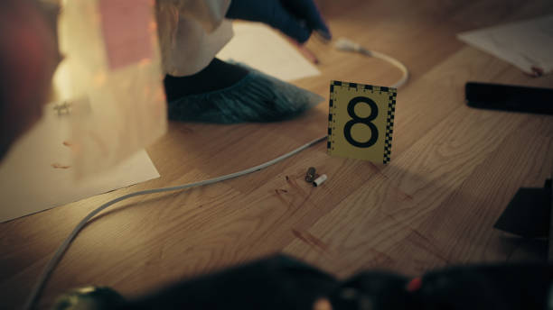 Close-up of a bullet case the floor near crime scene marker with number 8, and an expert is collecting evidence Close-up of a bullet case the floor near crime scene marker with number 8, and an expert is collecting evidence evidence bag stock pictures, royalty-free photos & images