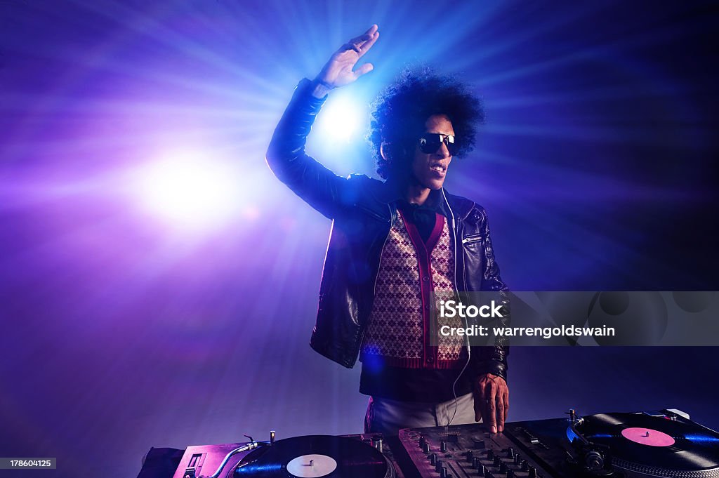 A DJ playing music at a nightclub party nightclub dj playing music on deck with vinyl record headphones light flare clubbing party scene Adult Stock Photo