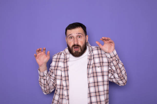 istock Young handsome bearded man feeling terrified, backing off and screaming in horror and panic, reacting to a nightmare on purple background. 1786046333