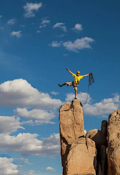 Rock climber balances on the summit after a successful and challenging ascent.