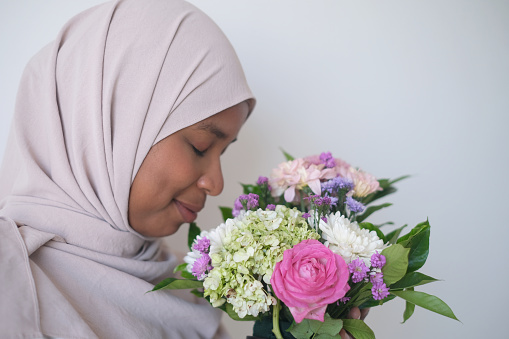 Portrait shot of a beautiful muslim woman enjoying the smell of fresh flowers