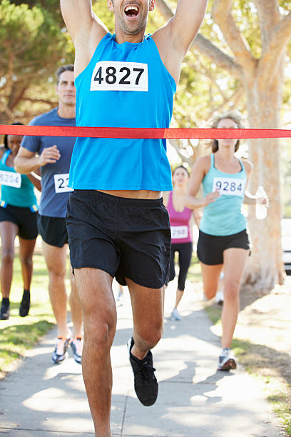 istock Male runner crossing red tape arms raised winning marathon 178607041