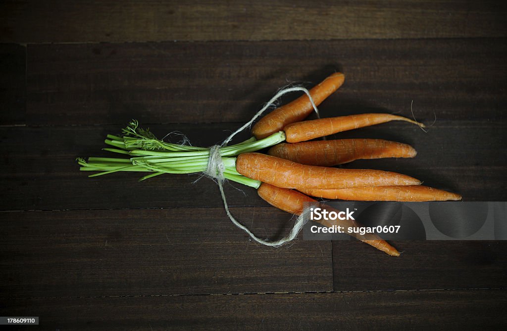 Cenouras com folhas verdes, amarrado em madeira marrom - Foto de stock de Adulação royalty-free