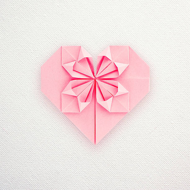 Pink paper origami heart on white canvas background stock photo