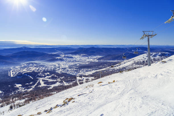 Winter nature panorama with Sheregesh ski resort in Altai, Russia, picturesque nature, sun flare on blue sky, white snow slopes and ski track, top view with range mountains, forest, perspective Winter nature panorama with Sheregesh ski resort in Altai, Russia, picturesque nature, sun flare on blue sky, white snow slopes and ski track, top view with range mountains, forest, aerial perspective 3610 stock pictures, royalty-free photos & images