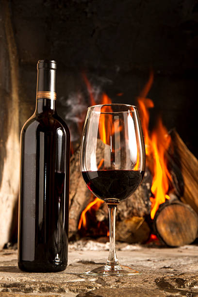 istock Red Wine cup and bottle with fireplace on the background. 178613240