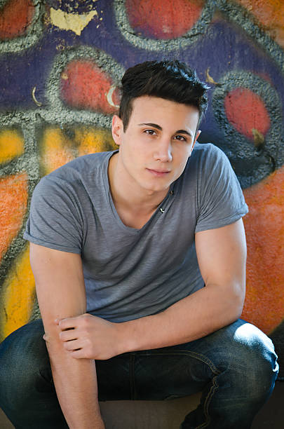 istock Handsome young man sitting against graffiti wall 178614713