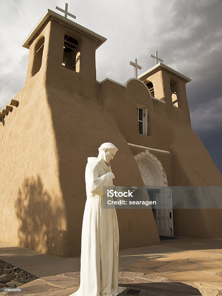 Saint Francis Statue With Church A marble statue of St. Francis in contemplation stands in front of the San Francisco de Asis Mission Church in Rancho de Taos in New Mexico. St. Francis of Assisi Stock Photo