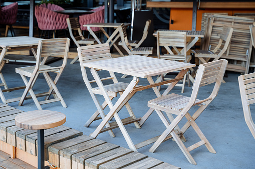 Wooden table with chairs in an outdoor cafe, a place for lunch on a summer day, a city restaurant on the sidewalk, an empty breakfast table. High quality photo