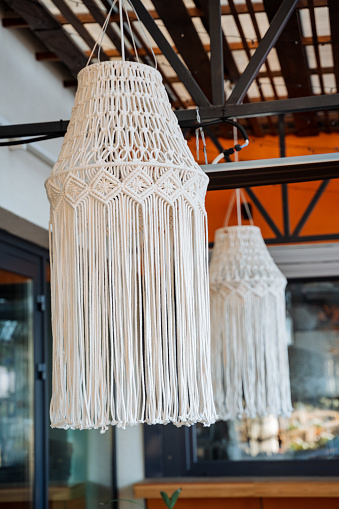 Designer chandelier in the cafe, boho style in the interior of the house, street restaurant, handmade, wicker cord rope hanging on the ceiling. High quality photo
