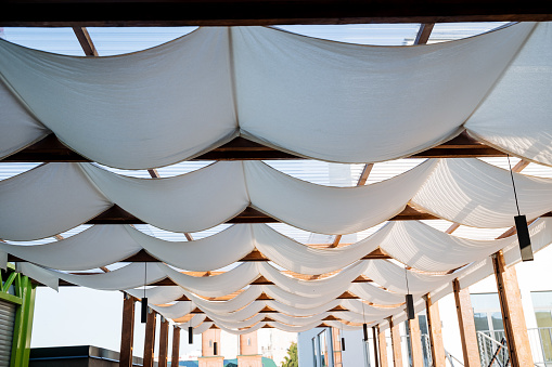Patio made of white fabric on the roof, the design of an outdoor restaurant in the open air, the protection of cafe visitors in the summer heat, a place to relax in the shade. High quality photo
