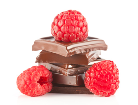 Three pieces of chocolate and raspberries on a white background.