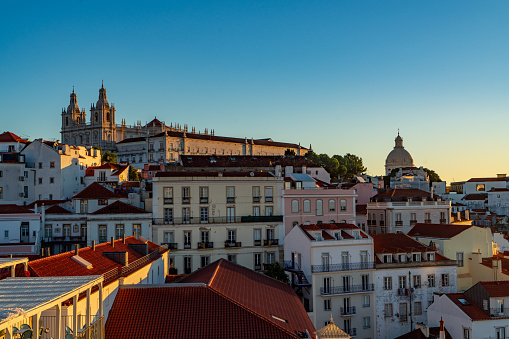 View over Lisbon with the courtyard at the church of São Vicente de Fora in the foreground. Richly decorated with azulejos tiles.\nIn the distance the The Ponte 25 de Abril over the Rio Tejo can be seen.